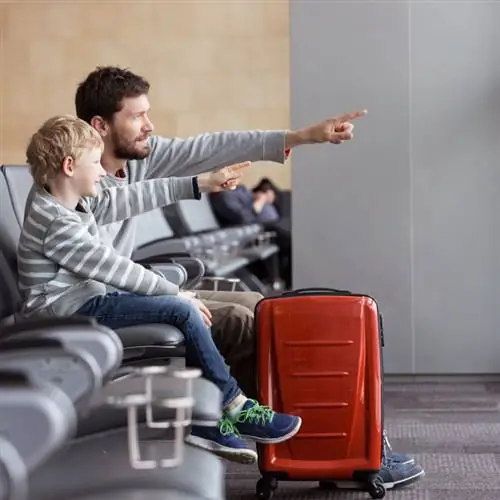 улыбающийся мальчик и его отец ждут в аэропорту