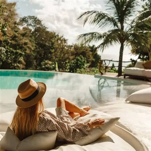 женщина в шляпе отдыхает у бассейна