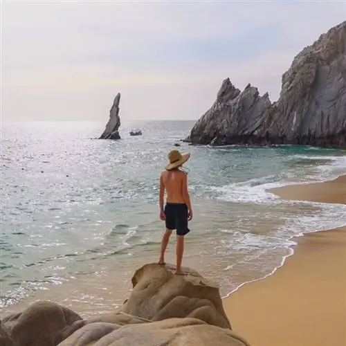 Молодой турист-мужчина, стоящий на скале на пляже, Южная Нижняя Калифорния, Тихоокеанское побережье Мексики