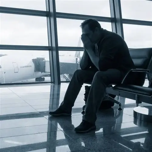 Мужчина расстроен в аэропорту из-за задержки или отмены рейса, срыва рейса, хаоса в путешествии