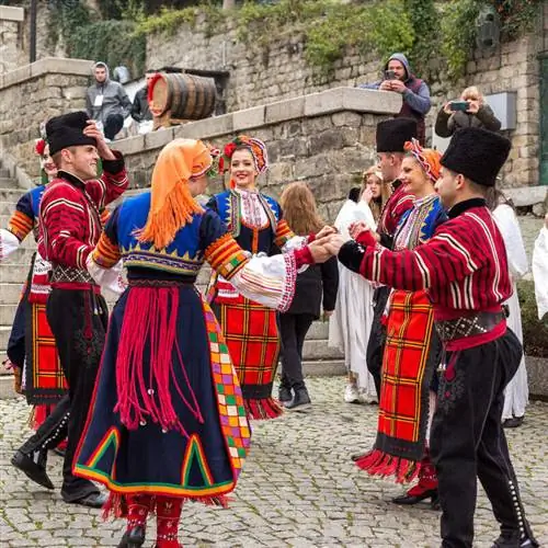Счастливые болгарские танцоры в традиционной этнической одежде в центре Пловдива, Болгария