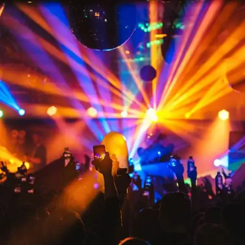 люди танцуют на рейве под яркими огнями вокруг