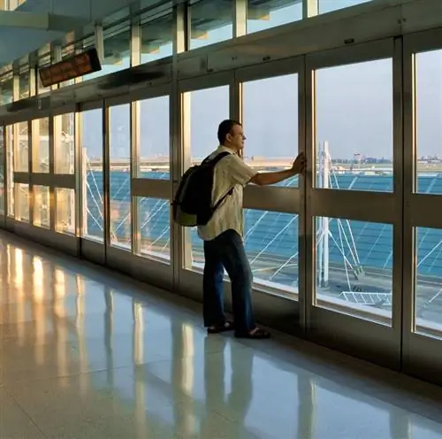 Мужчина стоит в терминале аэропорта Торонто и смотрит на самолеты