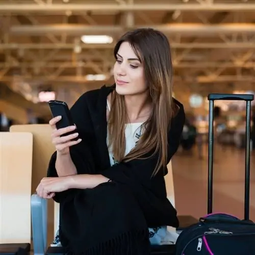 Молодая женщина пользуется телефоном в аэропорту