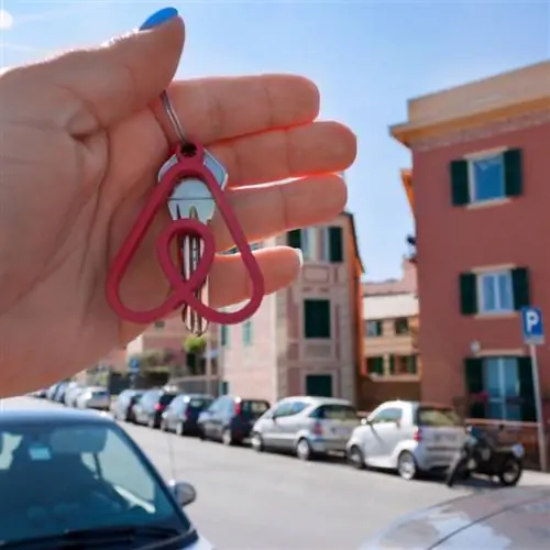 человек держит ключ перед объектом недвижимости Airbnb
