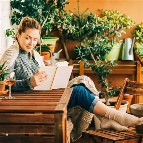 женщина отдыхает на открытом воздухе, читает книгу и пьет вино