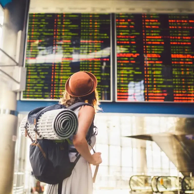 женщина с рюкзаком проверяет статус рейса в аэропорту