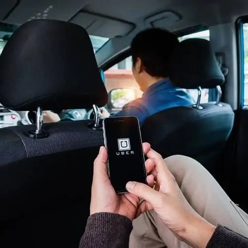 Путешественник проверяет приложение Uber во время поездки на Uber, концептуальное изображение Uber