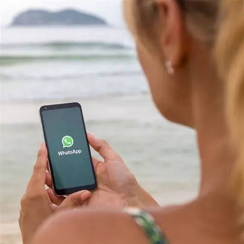 Молодая женщина заходила в WhatsApp на пляже