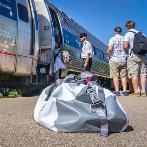 Пассажиры садятся в поезд Amtrak с багажом, изображенным на полу станции, концепция путешествия на поезде Пассажиры садятся в поезд Amtrak с багажом, изображенным на полу станции, концепция путешествия на поезде