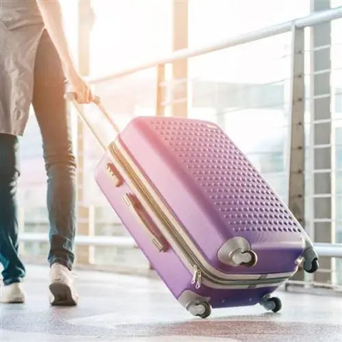 Молодая женщина путешествует с чемоданом рано утром в аэропорту