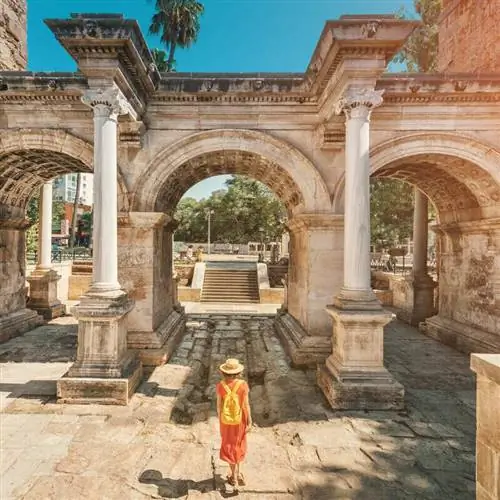 Молодая туристка пересекает ворота Адриана в Калеичи, Старый город Анталья, Турция