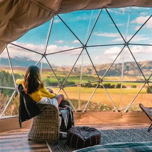 Женщина смотрит из окна роскошной палатки, глэмпинг