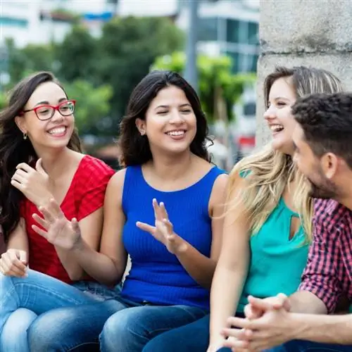 Группа молодых людей сидит на скамейке и вместе тренируется говорить по-испански.