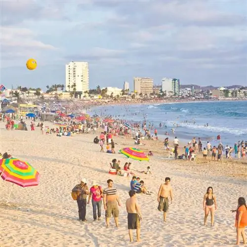 Переполненный пляж в Мексике с океаном и отелями вдалеке