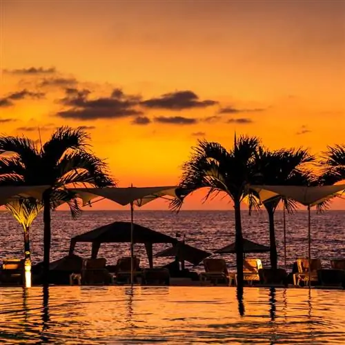 Пуэрто-Вальярта, Мексика: закат с видом на бассейн и пляж с оранжевым небом в популярном мексиканском туристическом месте.