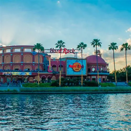 Hard Rock Cafe на фоне заката на курорте Universal Orlando Resort во Флориде с озером на переднем плане.