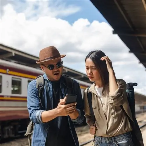 Два путешественника, расстроенные, смотрят на мобильный телефон на вокзале