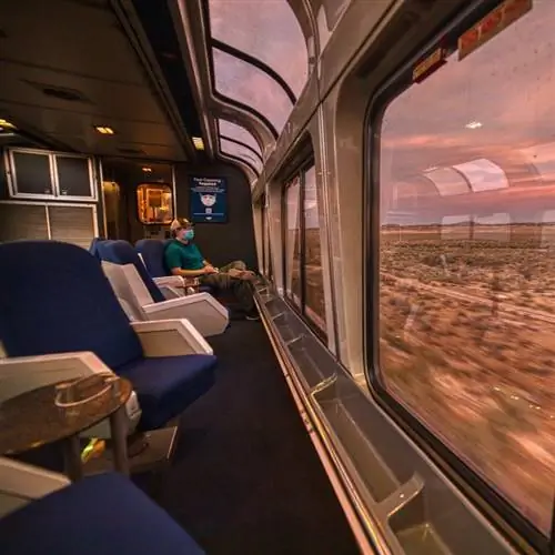 Путешественник наслаждается пейзажами во время заката с поезда Amtrak