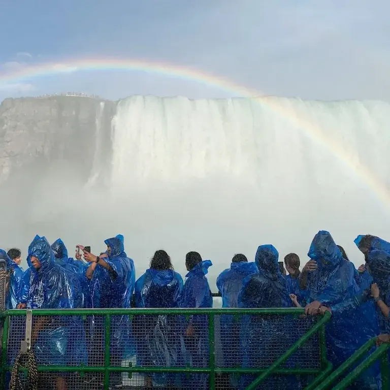 Путешественники наслаждаются видом на Ниагарский водопад под радугой
