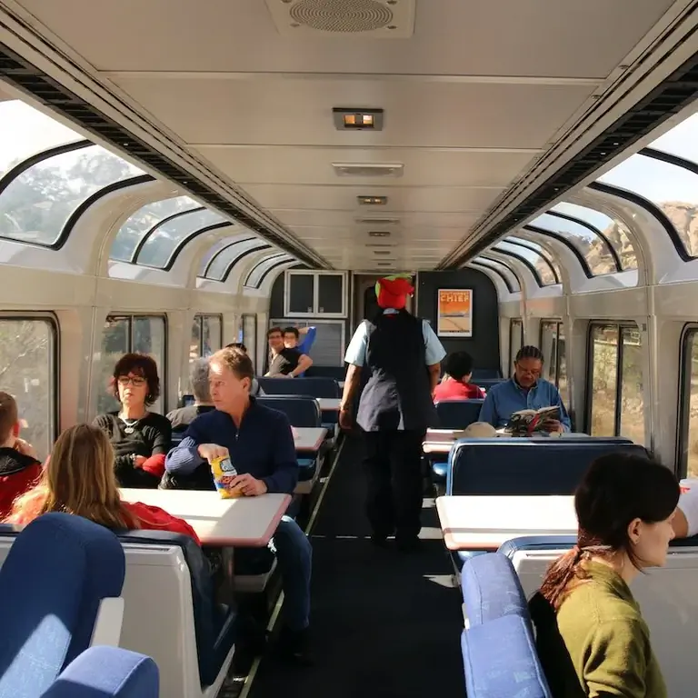 Пассажиры сидят в поезде в зоне со столиками