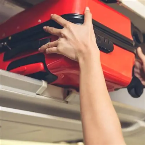 Бортпроводники поднимают багажную сумку в самолете. Концепция авиаперевозок и туризма.