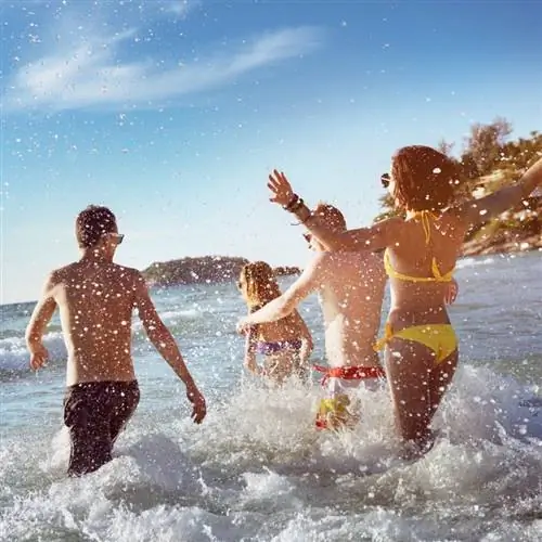 Счастливые друзья прыгают в море во время пляжного отдыха