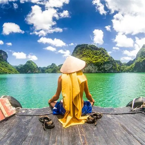 Вьетнамец сидел на пирсе во вьетнамской шляпе, любуясь видом на залив во Вьетнаме, Юго-Восточная Азия