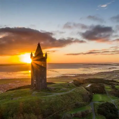 Башня Скрабо на снимке, когда за ней восходит солнце, Северная Ирландия, Великобритания