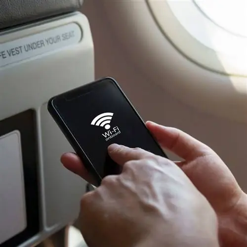 Молодой путешественник-мужчина подключается к сети Wi-Fi во время полета внутри самолета