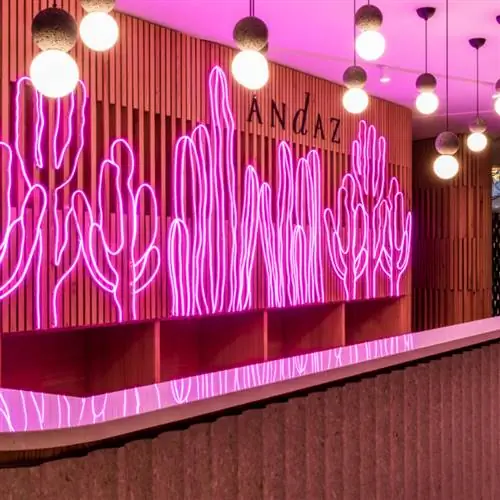 Стойка регистрации Andaz Mexico City Condesa подсвечена фиолетовыми неоновыми огнями кактусов и круглыми огнями наверху.