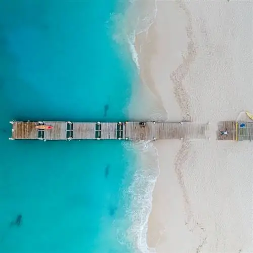 Деревянный причал выходит в море на пляже Грейс Бэй в Терксе и Кайкосе.