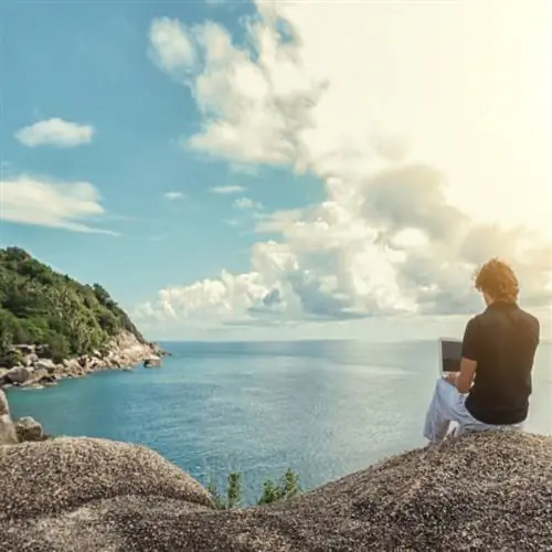 Мужчина с ноутбуком на скалах на берегу моря