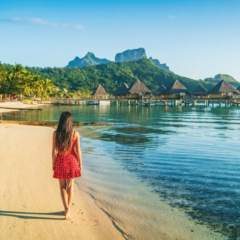 Женщина гуляет по пляжу Бора-Бора
