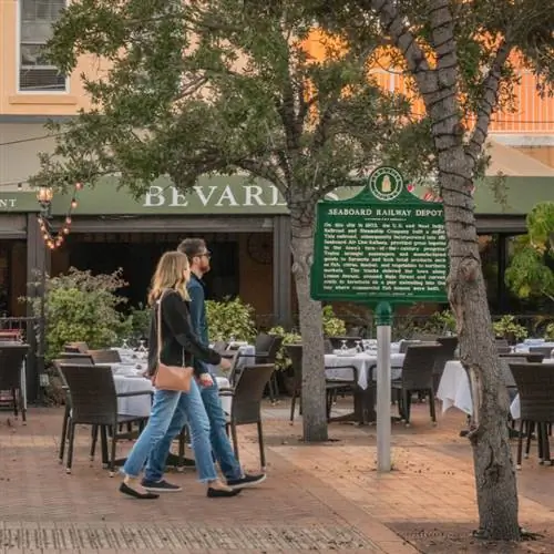 Молодая пара проходит мимо ресторана со столиками на свежем воздухе в историческом центре города.