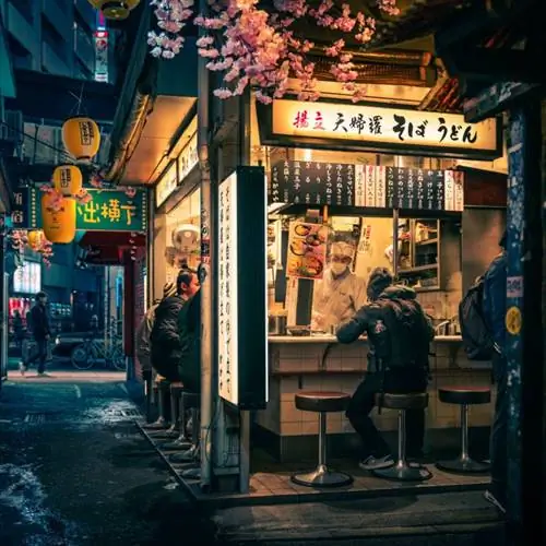 посетитель сидит на табурете на открытом воздухе в ресторане-баре в Токио