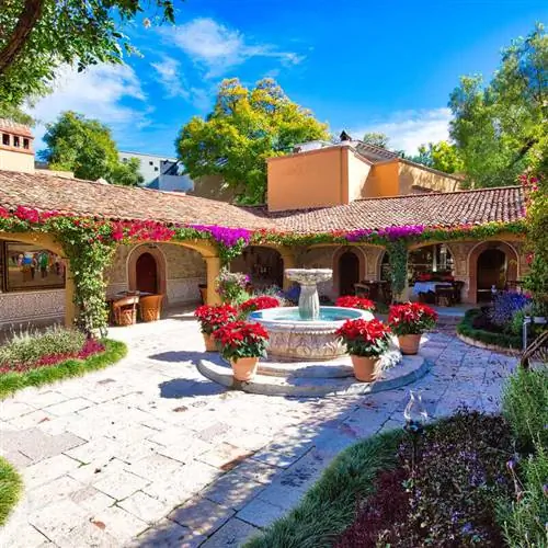 Красивый внутренний двор с изысканным фонтаном, украшенным цветочными вазами в Сан-Мигель-де-Альенде, Гуанахуато, Мексика