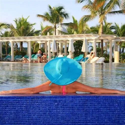 'Женщина в синей шляпе сидит в бассейне тропического курорта 