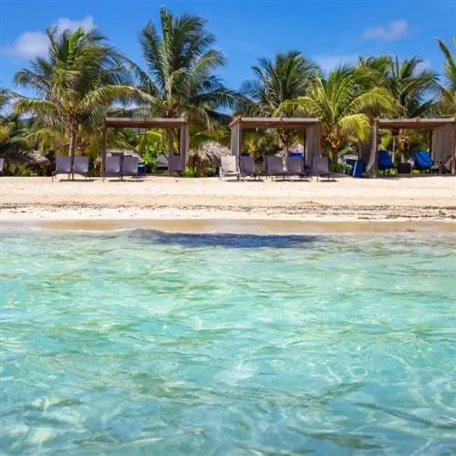 Вид на пляж с белым песком, пальмами и беседками со стороны океана