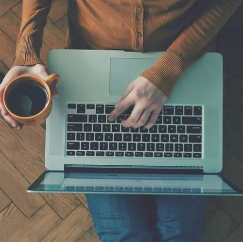 Женщина пользуется ноутбуком и пьет кофе