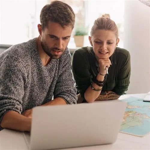 Два путешественника смотрят на ноутбук, планируя поездку.