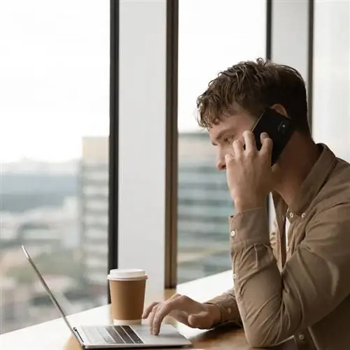 Мужчина разговаривает по телефону за компьютером