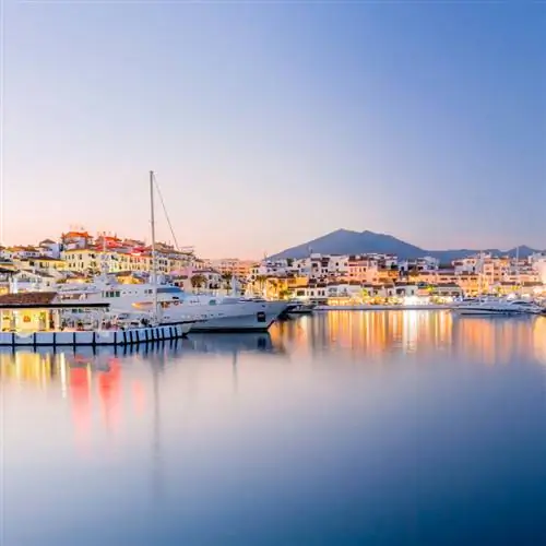 Док Марбельи с припаркованной большой яхтой и горами сзади.