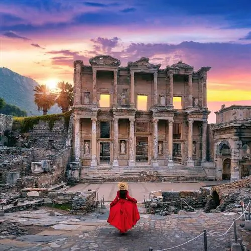 Молодая женщина в красном платье идет к библиотеке Цельса в Эфесе, древнем греко-римском городе в Сельчуке, провинция Измир, Турция, Турция, Ближний Восток, Восточная Европа, Западная Азия