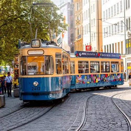 Желто-синий трамвай движется по улице в Мюнхене, Германия.