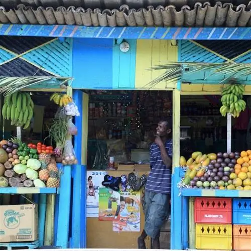 Мужчина стоит перед своим местным фруктовым киоском в Очо-Риос, Ямайка.