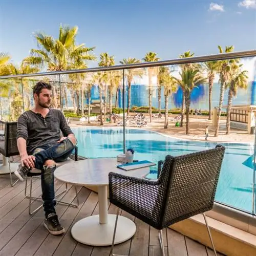 Турист сидит у бассейна в отеле на Мальте