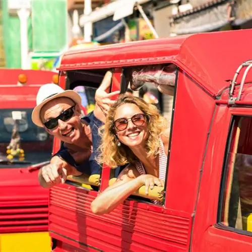 Двое туристов высовывают головы из красного тук-тука на Пхукете, Таиланд.