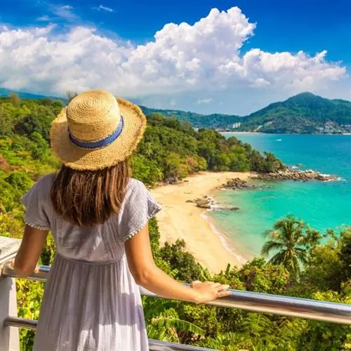 Женщина, стоящая на балконе, смотрит на пляж в Пхукете, Таиланд.