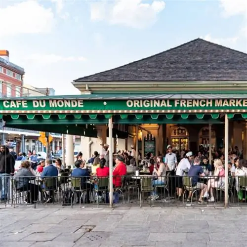 Люди сидят за столиками в знаменитом ресторане Cafe Du Monde